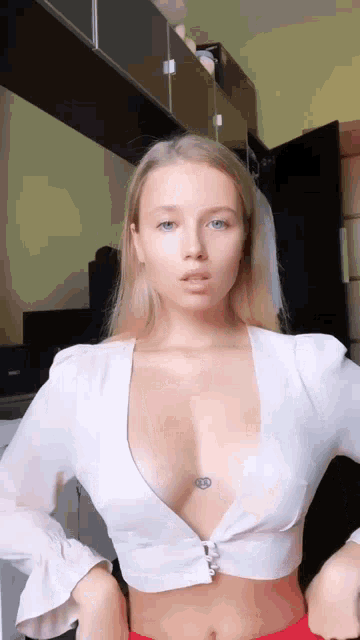 a woman with a tattoo on her chest is wearing a very revealing white top .