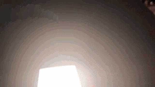a person is holding a light bulb in a dark room and it is shining brightly .