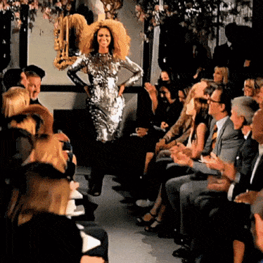 a woman in a sequined dress is walking down a runway