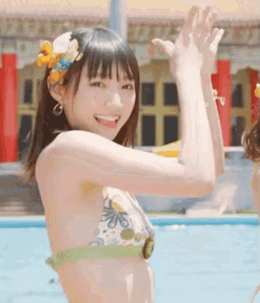 a woman in a bikini is clapping her hands in the air