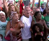 a crowd of people are standing in a line with their arms in the air .