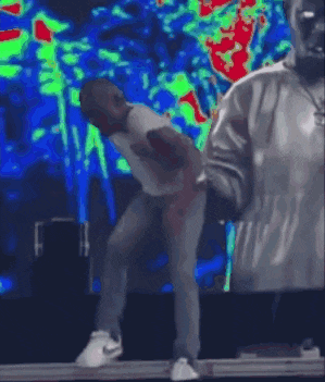 a man is dancing on stage while holding a microphone .