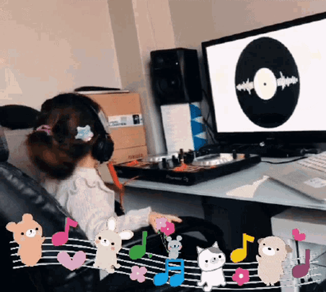 a little girl wearing headphones sits in front of a computer monitor