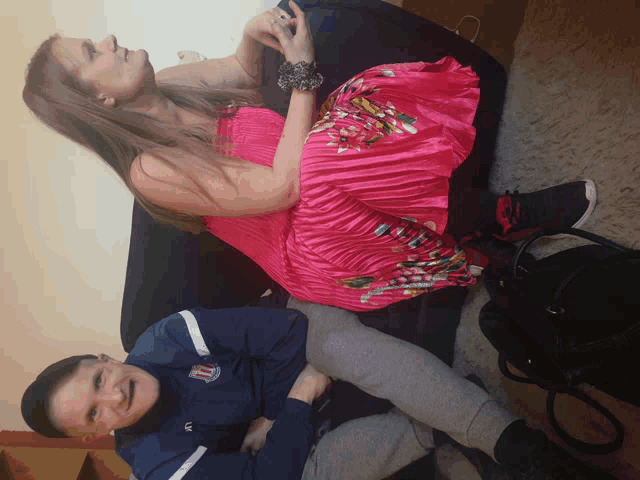 a woman in a pink pleated dress sits next to a man in a blue shirt with the number 11 on it