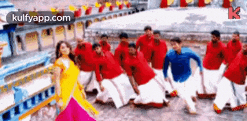 a group of people in red shirts and white pants are dancing together .