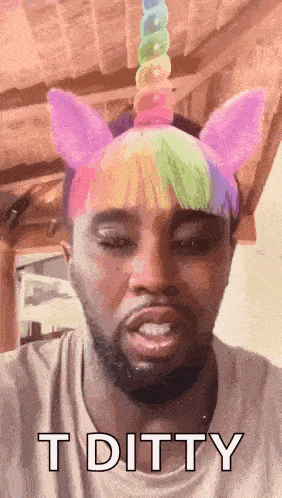 a man wearing a unicorn headband with rainbow hair and ears is making a funny face .