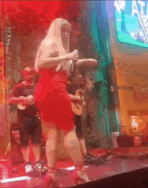 a woman in a red dress is singing into a microphone on stage