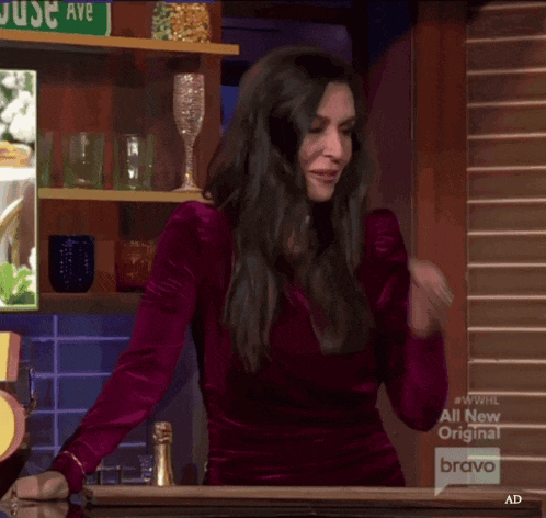 a woman in a purple dress is standing in front of a bar with a sign that says just ave on it