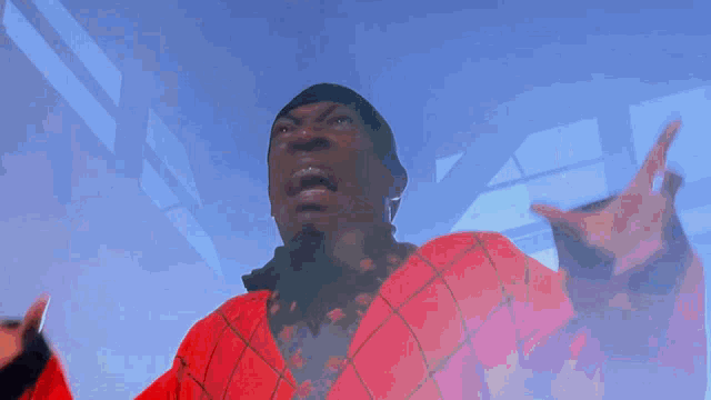 a man in a red jacket is looking up with his hands outstretched