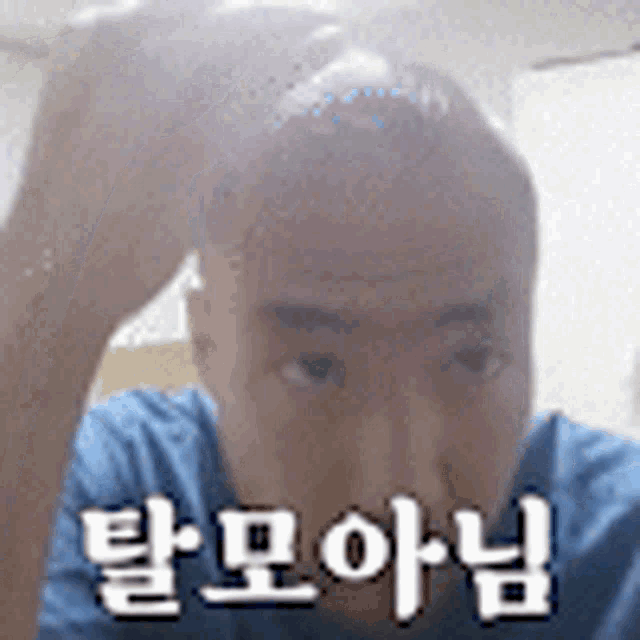 a man in a blue shirt is looking at the camera with a foreign language written on his face .