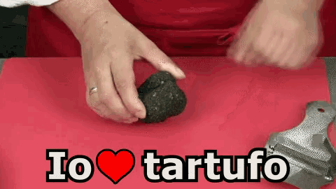 a person is holding a truffle on a red cutting board with the words i love tartufo