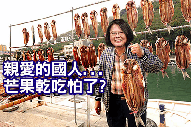 a woman holds a large fish in front of a bunch of fish hanging on a rack