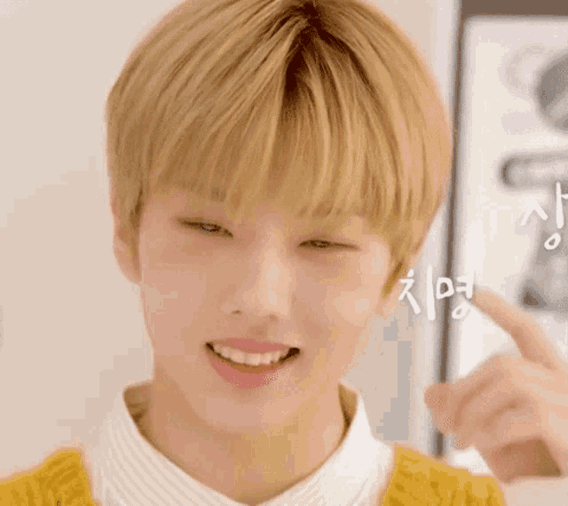 a close up of a young man with blonde hair and a yellow sweater .