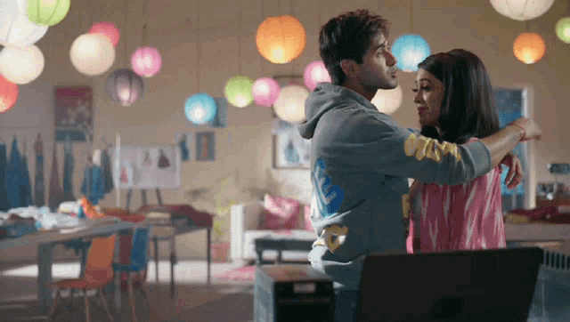 a man and woman are hugging in a room with lanterns and a laptop