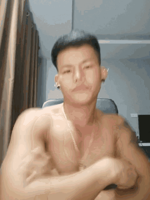 a shirtless man with a gold chain around his neck is flexing his muscles