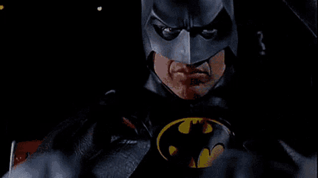 a close up of a man in a batman costume with a bat symbol on his chest