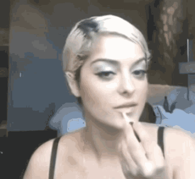 a woman is applying lipstick to her lips in a room .