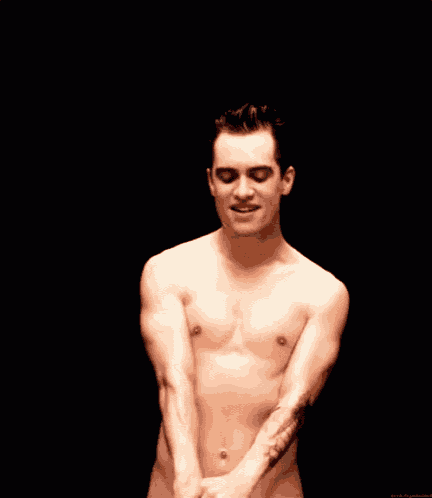 a shirtless man with a tattoo on his arm is smiling .