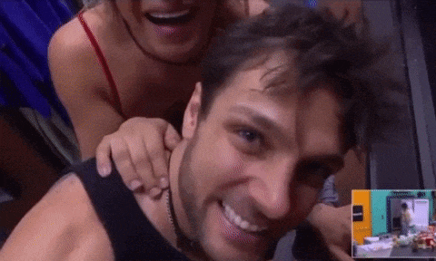 a woman is putting her arm around a man 's neck while he smiles .