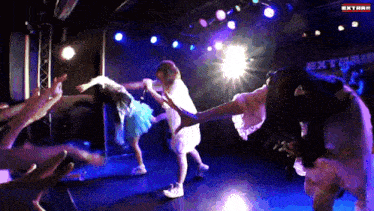 a group of people dancing in front of a sign that says extram on it