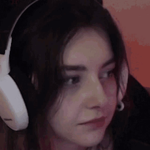 a woman is wearing headphones and looking at the camera .