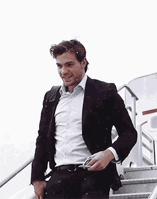 a man in a suit is smiling while walking up stairs
