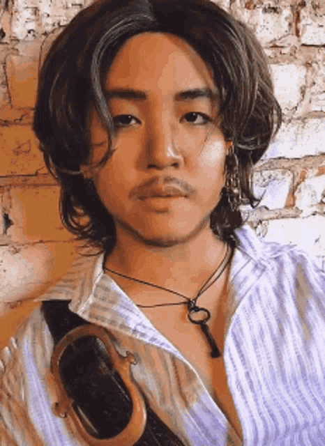 a man with long hair and a beard is wearing a necklace with a key on it