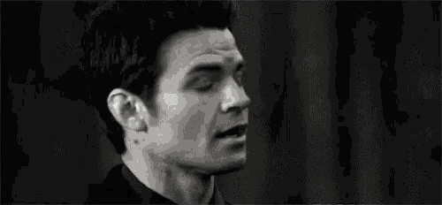 a close up of a man 's face in a black and white photo with his mouth open .