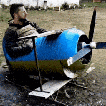 a man is sitting in a small blue and yellow airplane with a propeller