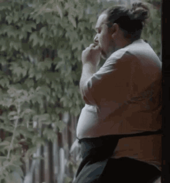 a man is sitting in front of a window and eating a sandwich .