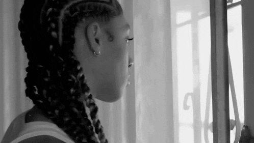 a black and white photo of a woman looking out a window .