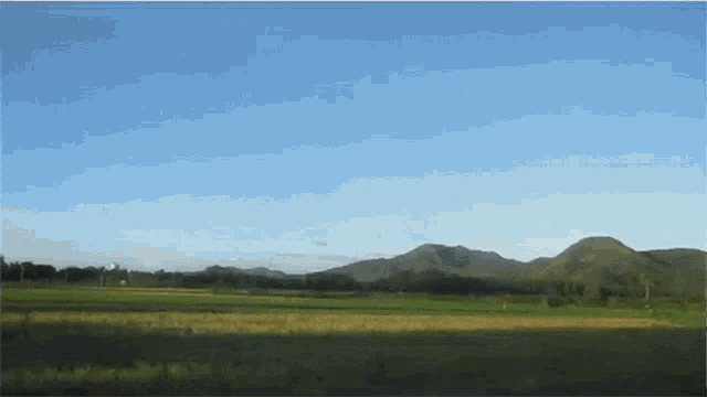 a landscape with mountains in the distance and a blue sky
