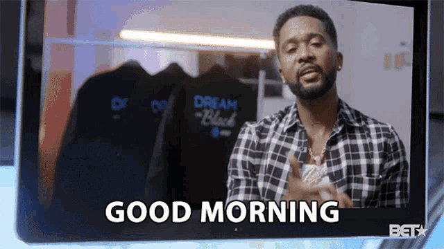a man in a plaid shirt says good morning on a screen