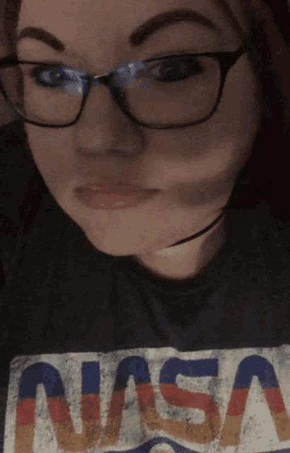 a girl wearing glasses and a nasa shirt