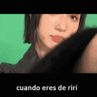 a close up of a woman 's face with a green background and the words `` cuando eres de riri '' .