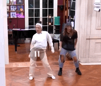 a couple of women are dancing in a living room .