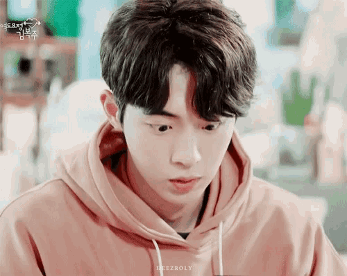 a young man in a pink hoodie is looking down at something .