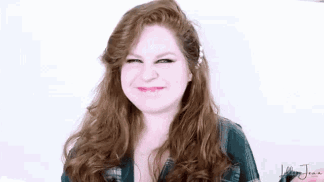 a woman with long red hair is smiling and making a face .