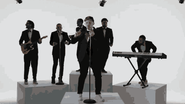 a group of men singing in front of a keyboard that says yamaha on it