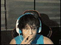 a man wearing headphones and a blue tank top is eating something