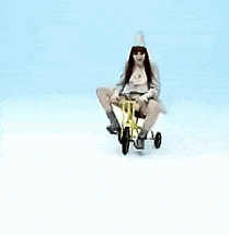 a woman is sitting on a yellow tricycle with her legs crossed