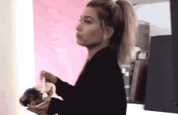 a woman in a black sweater is holding a bowl of food .