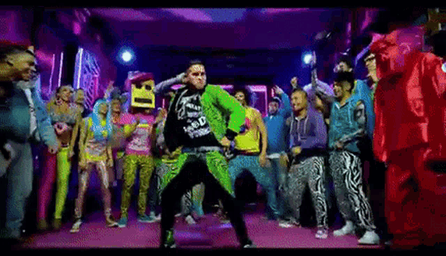 a man in a green jacket is dancing in front of a group of people .