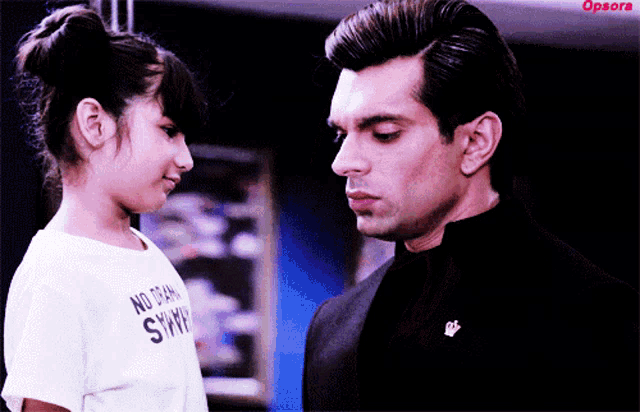 a little girl wearing a shirt that says no drama simps looks at a man