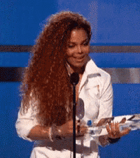a woman with long red hair is standing in front of a microphone holding a bottle of water