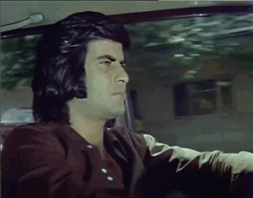 a man in a brown shirt is sitting in a car