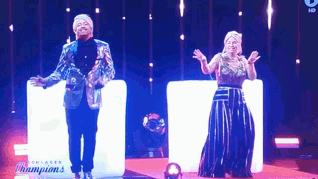 a man and a woman are dancing on a stage with the words champions on the bottom