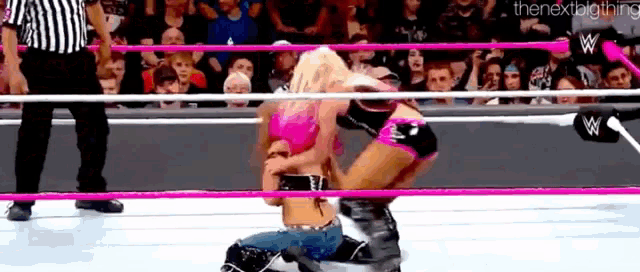two women are wrestling in a wrestling ring with a referee watching .