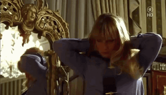 a woman is adjusting her hair in front of a mirror with the number 1 on it .