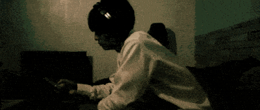 a man wearing headphones sits on a couch looking at his phone